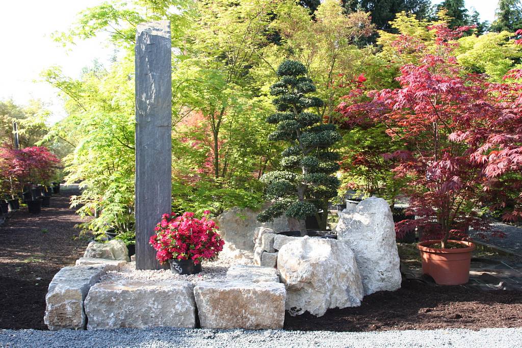 Große Bruchsteine aus Naturstein und eine große Stele im asiatischen Garten