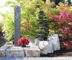 Große Bruchsteine aus Naturstein und eine große Stele im asiatischen Garten